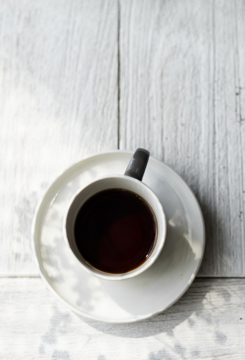 Free Image of Overhead view of a cup of coffee on white wood 