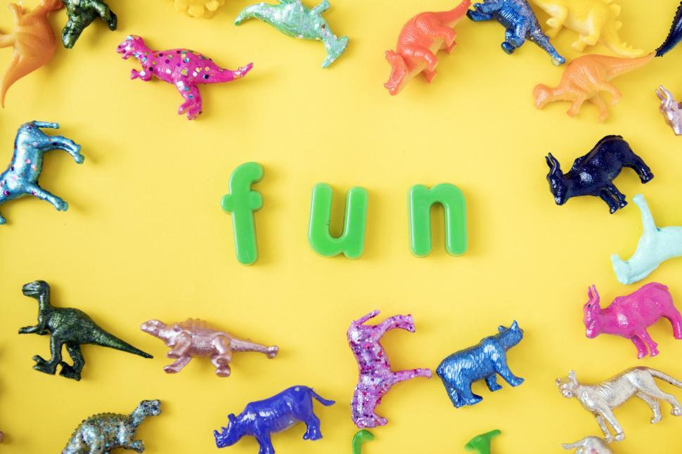 Free Image of Text - Fun surrounded with colorful toy animals on yellow surface 