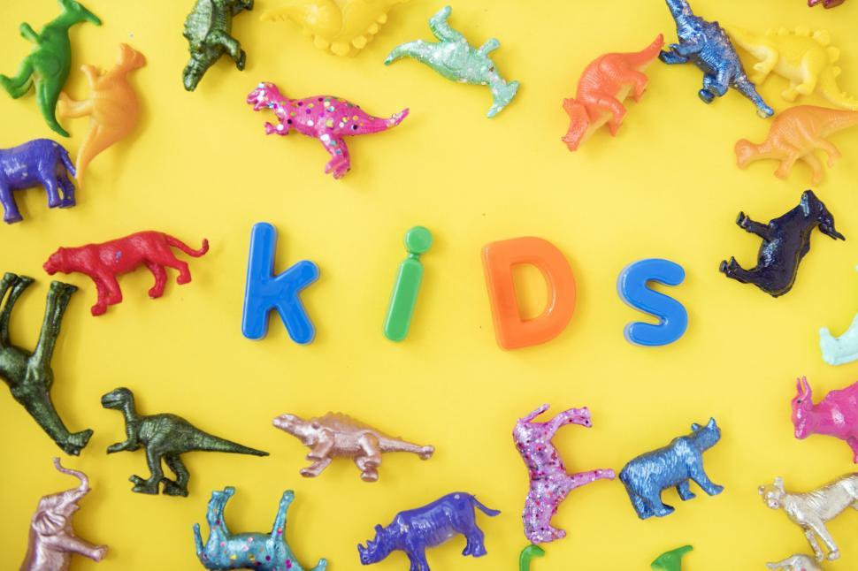 Free Image of Text - kids surrounded with colorful toy animals on yellow surface 