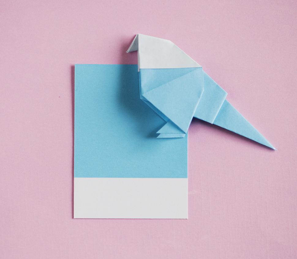Free Image of Flay lay of a folded paper bird on a spaced cardboard frame 