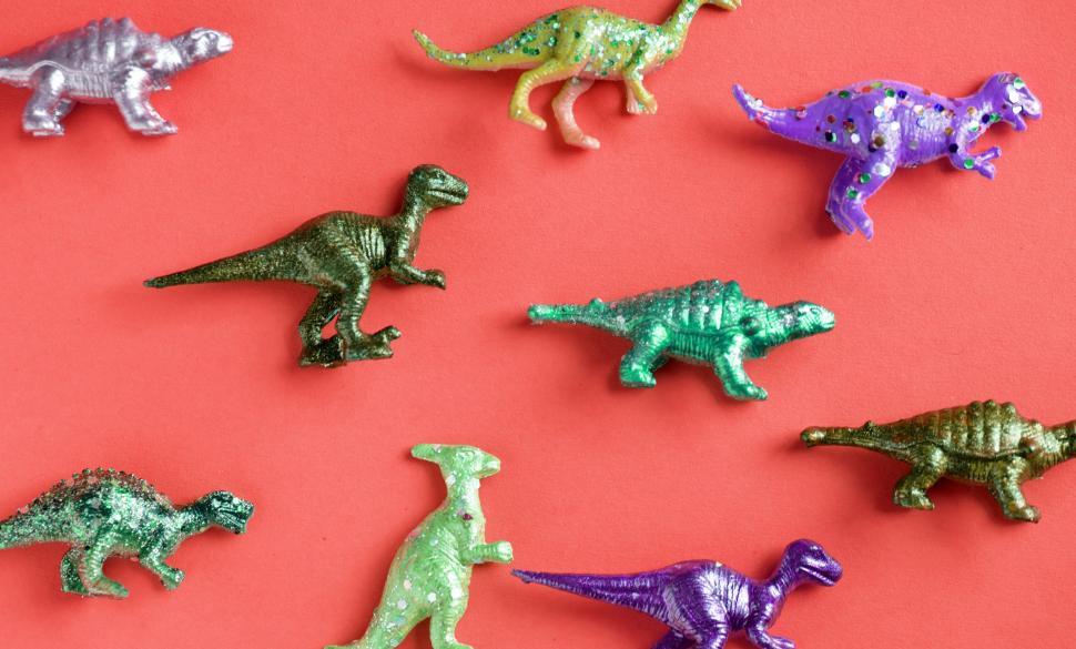 Free Image of Colorful toy dinosaurs on red surface 