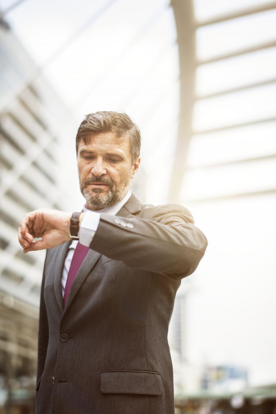 Free Image of An bearded businessman looks at time on his wristwatch 