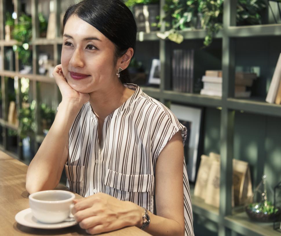 Free Image of An Asian woman enjoying coffee at a cafe 