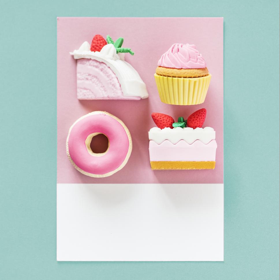 Free Image of Flay lay of fake cake, cupcake, doughnut and pastry on a spaced cardboard frame 