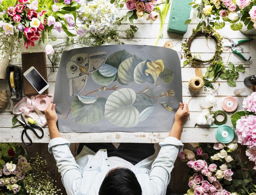 Free Image of Flat lay of a florist looking at illustration on paper 