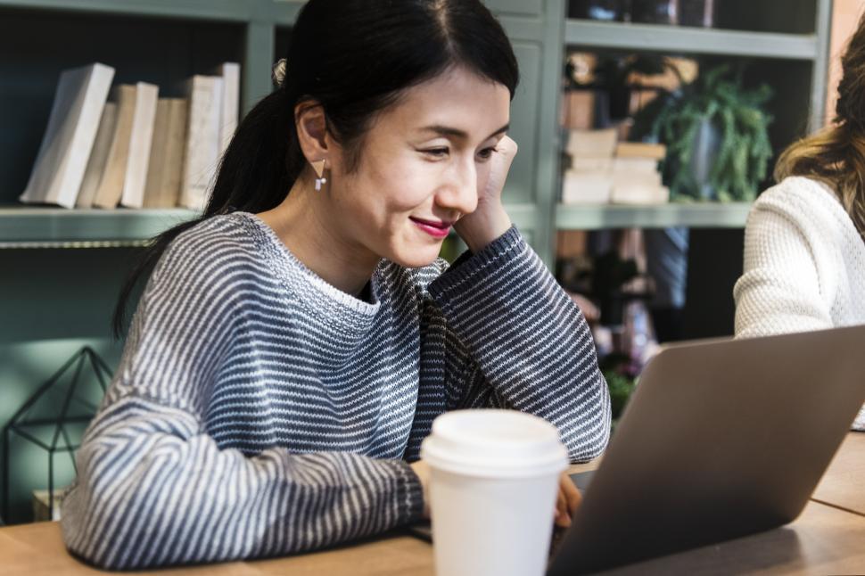 Free Image of A young woman in the office with coffee and laptop 