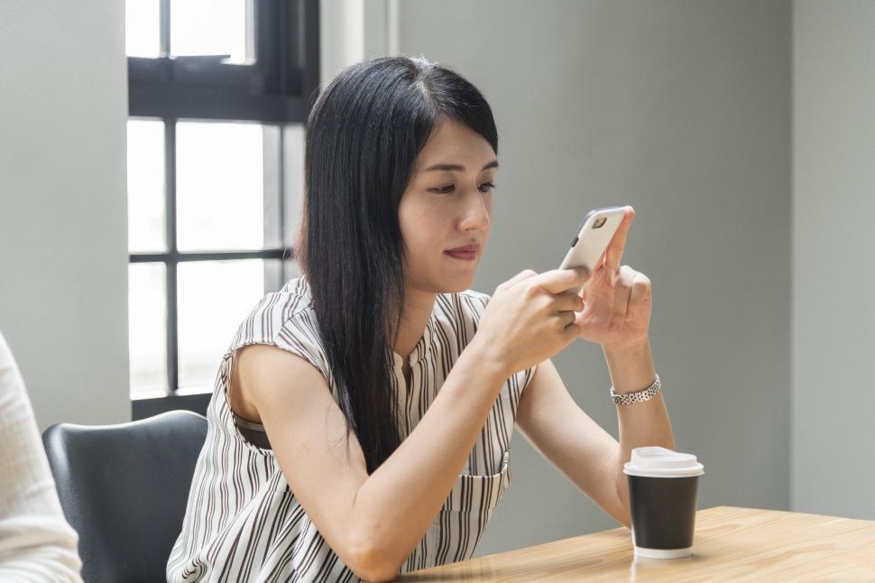 Download Free Stock Photo of An Asian ethnicity woman operating her mobile phone 