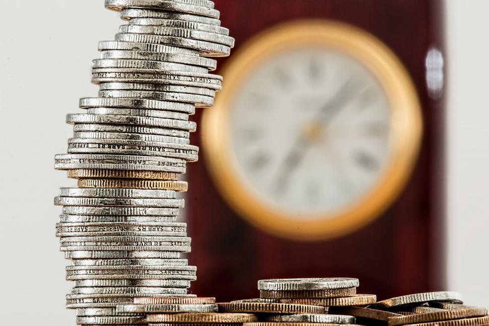 Free Image of Stack of Coins With Clock in Background 