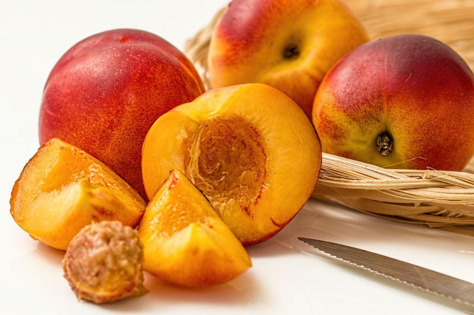 Free Image of Basket Filled With Sliced Peaches Next to a Knife 