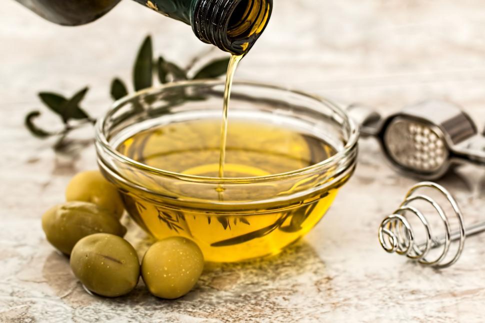 Free Image of Olive Oil Being Poured Into a Bowl of Olives 