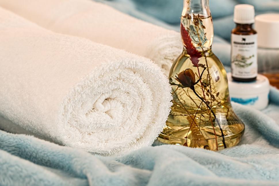 Free Image of Essential Oils Bottle and Towel on Bed 