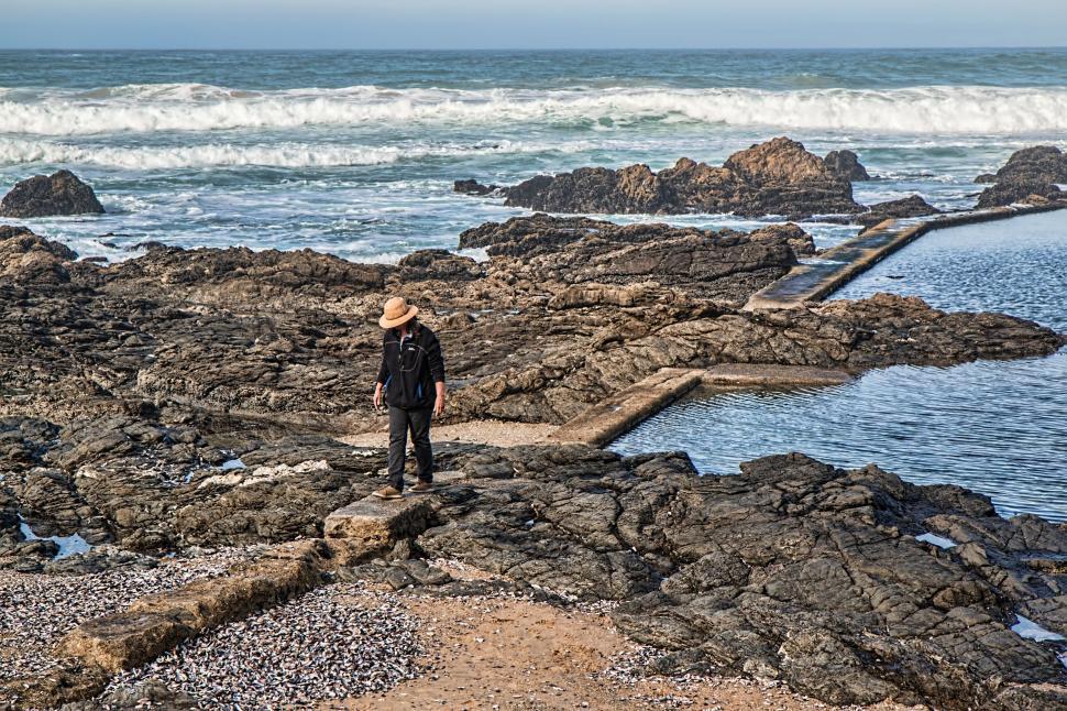 Free Image of Man Standing on Rocky Beach Next to Ocean 