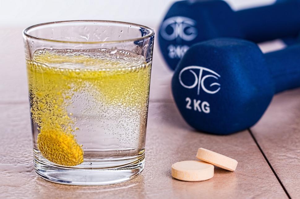 Free Image of Glass of Water With Yellow Substance and Blue Dumbbell Weight 