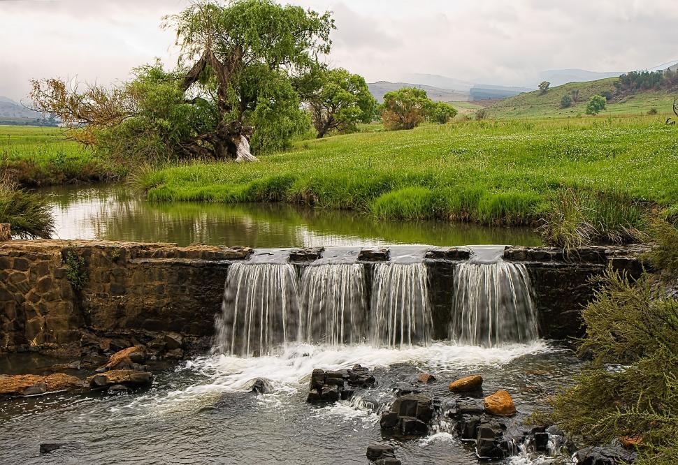 Free Image of Small Waterfall Flowing in Green Field 