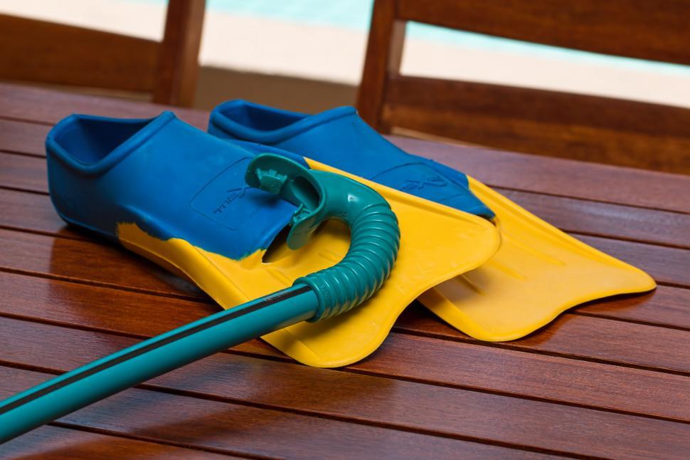 Free Image of Blue and Yellow Wetsuits on Wooden Table 