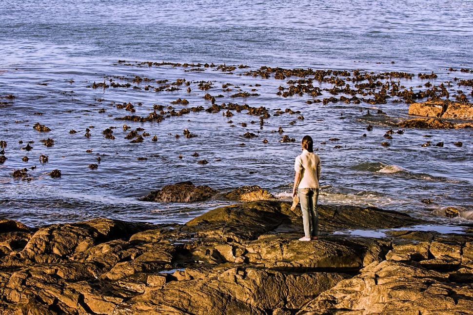 Free Image of Man Standing on Rocky Beach Next to Ocean 