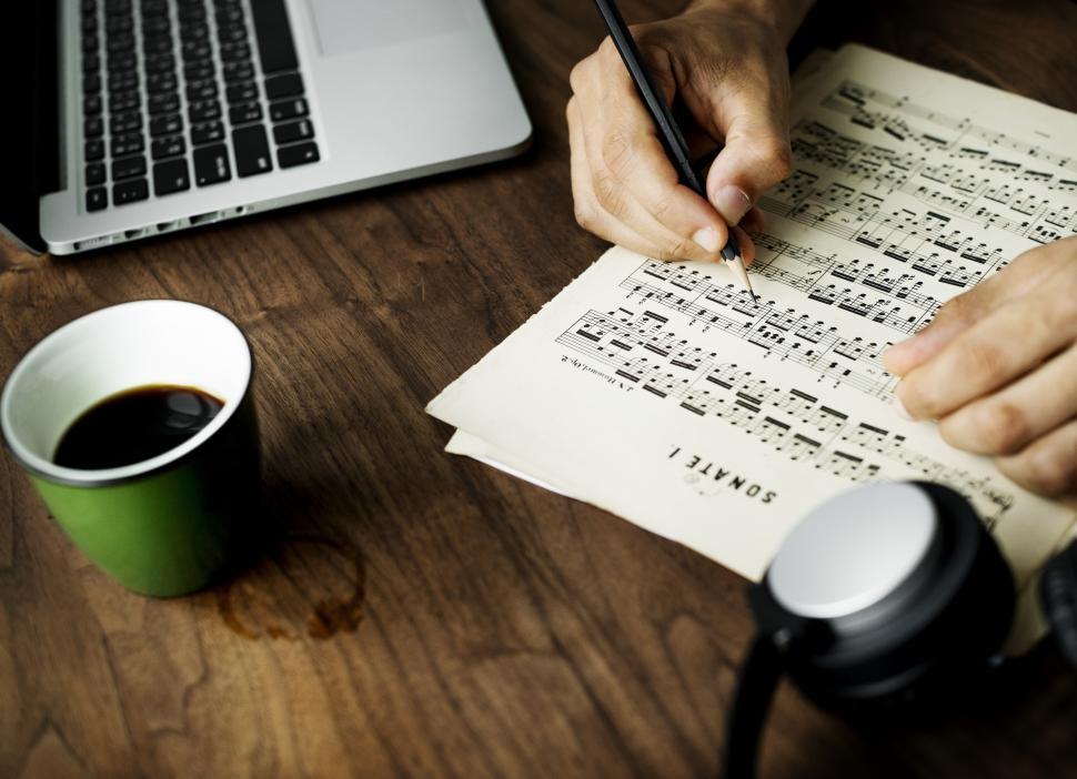 Free Image of Close up of a person writing musical notes on a sheet of paper 