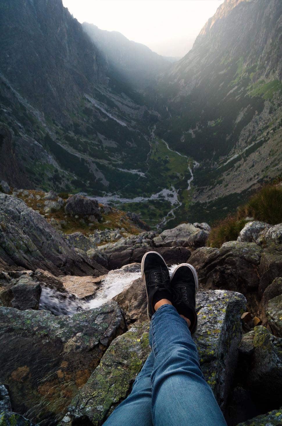 Free Image of Traveler sitting on rock and looking over Mountain 