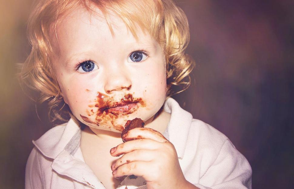 Free Image of Blue eyes baby eating chocolate  
