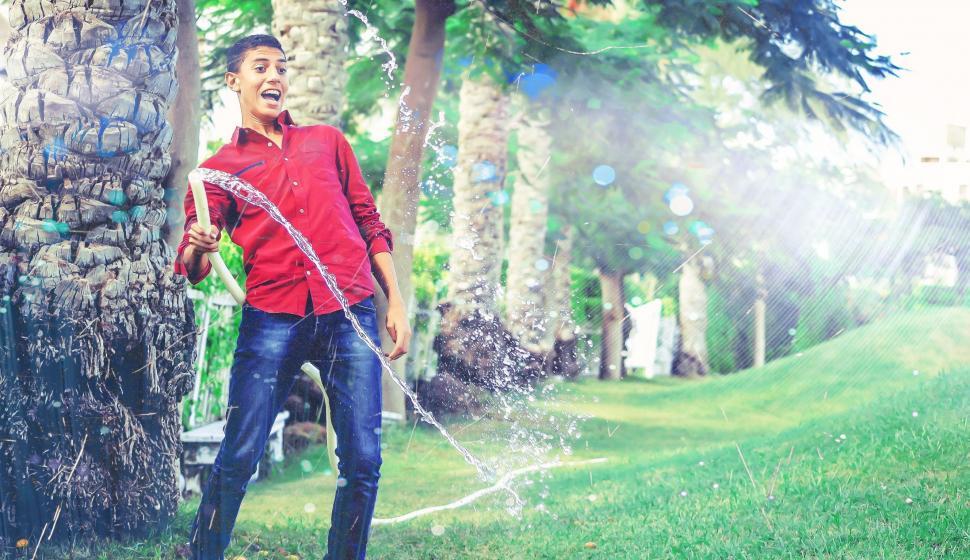 Free Image of Young Man playing with a garden hose  