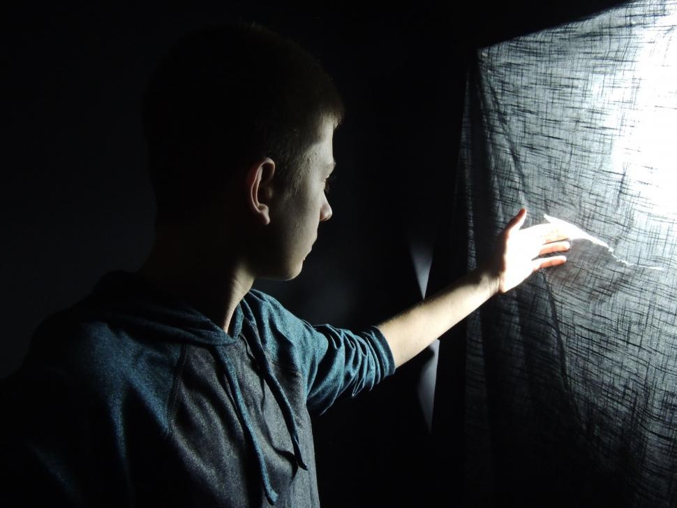 Free Image of Boy looking at torn curtain  