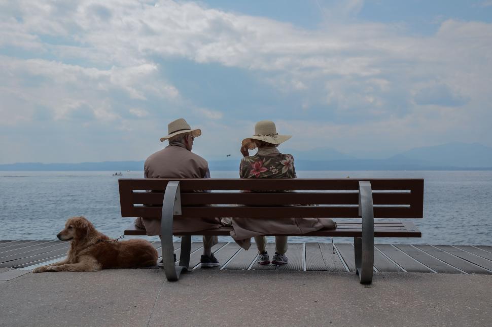 Download Free Stock Photo of Old elderly couple sitting on bench by beach 