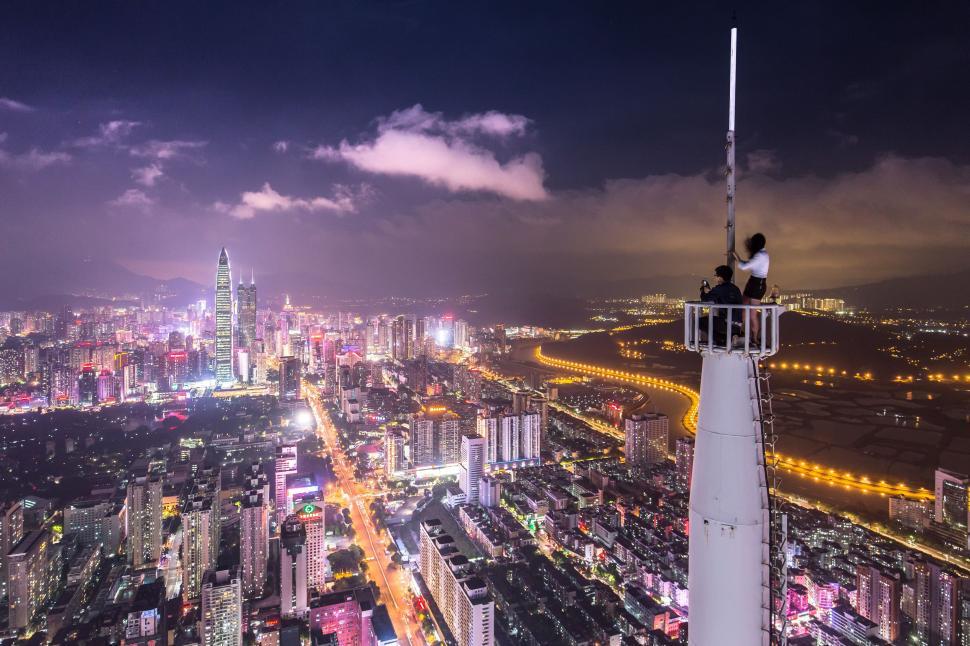 Free Image of Couple on tower on capture night lights of city  