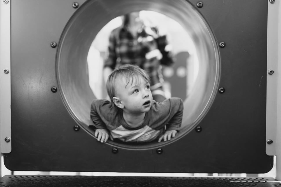 Free Image of Little Boy crawling in tunnel - black and white  