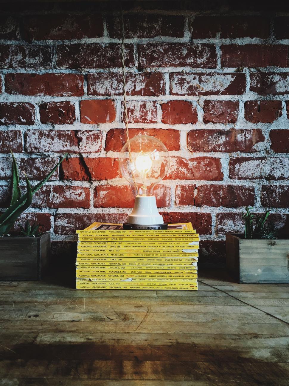 Free Image of Stack of Magazines and Bulb with Brick Wall  