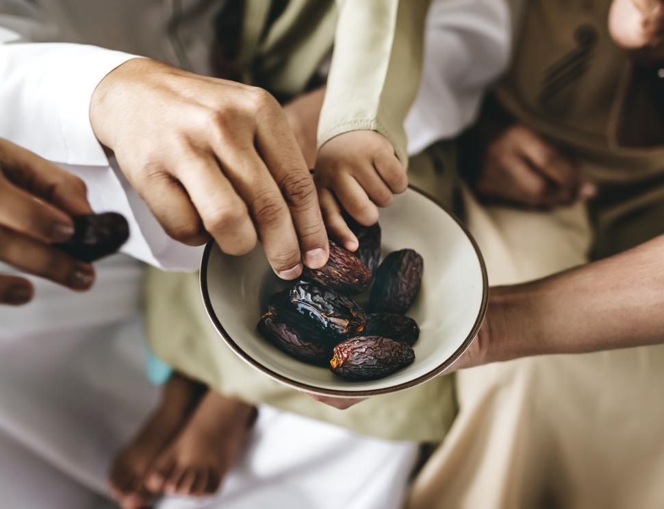Free Image of Close up - hands of people sharing a bowl of dates 