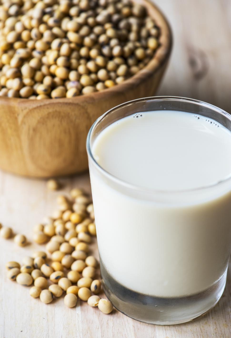 Free Image of Overhead view of a glass of soy milk alongside a bowl full of soybeans 