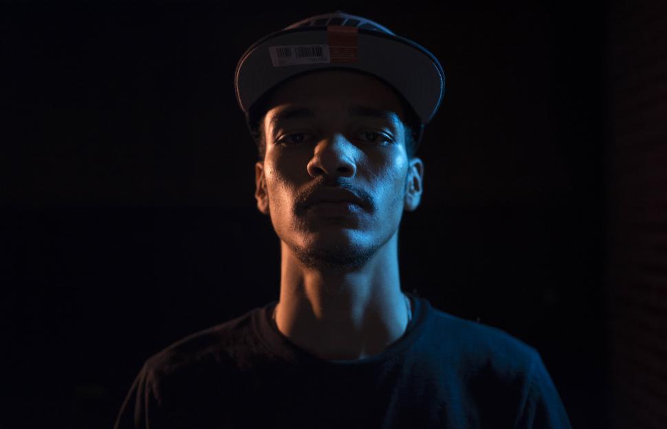 Free Image of Young Man in Black T-shirt and cap in dark room  