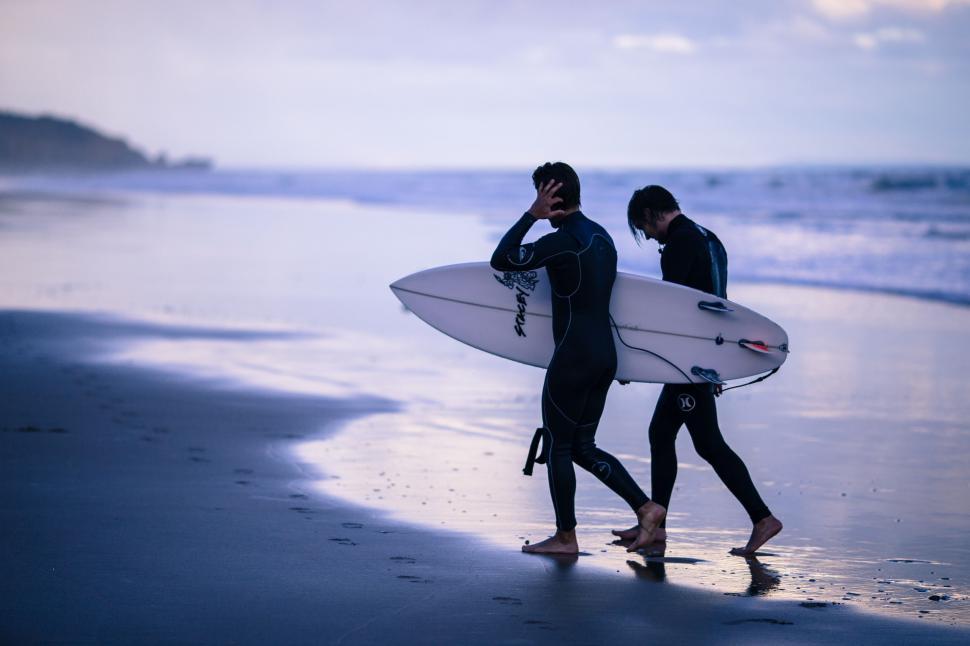 Free Image of Two Surfers wearing wetsuit at the beach  