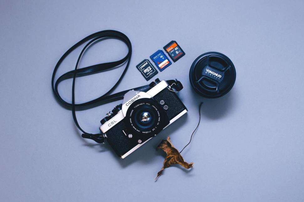 Free Image of Cosina Camera and dry leaf on white table  