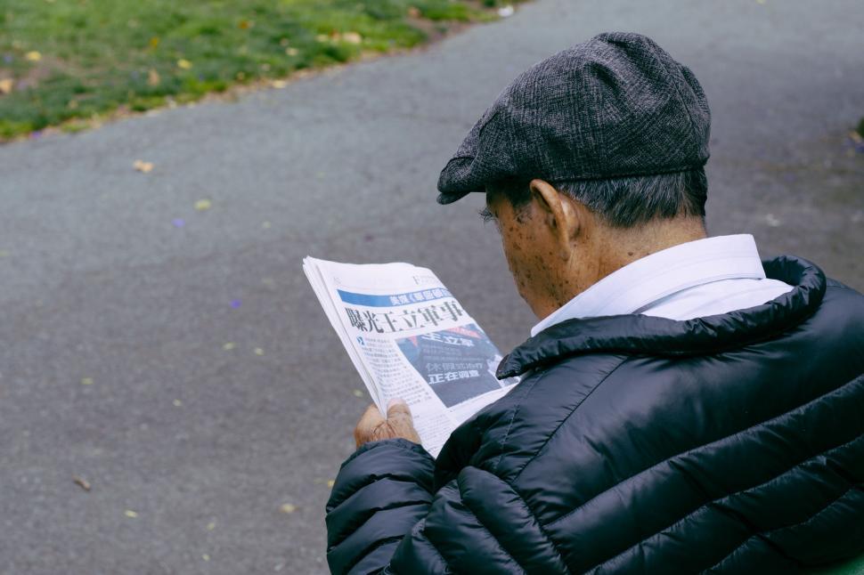 Free Image of Man in cap reading a newspaper  