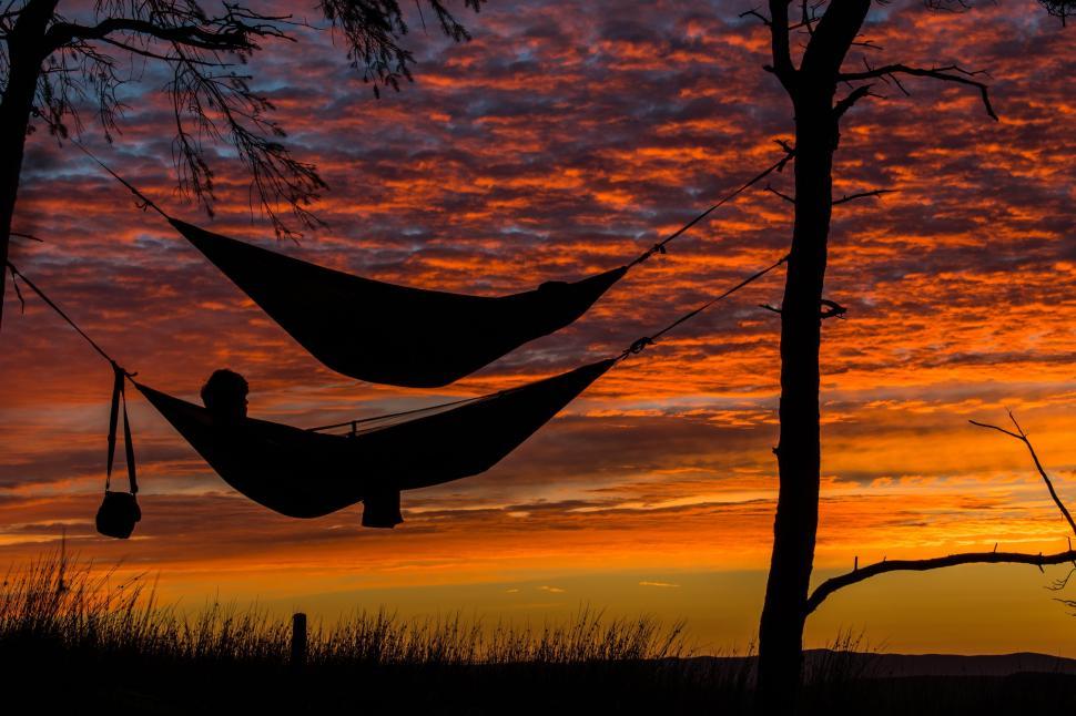 Free Image of Person relaxing on hammock during sunset  