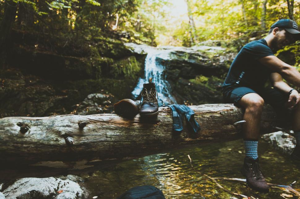 Free Image of Hiking Boots on Tree Trunk with waterfall  