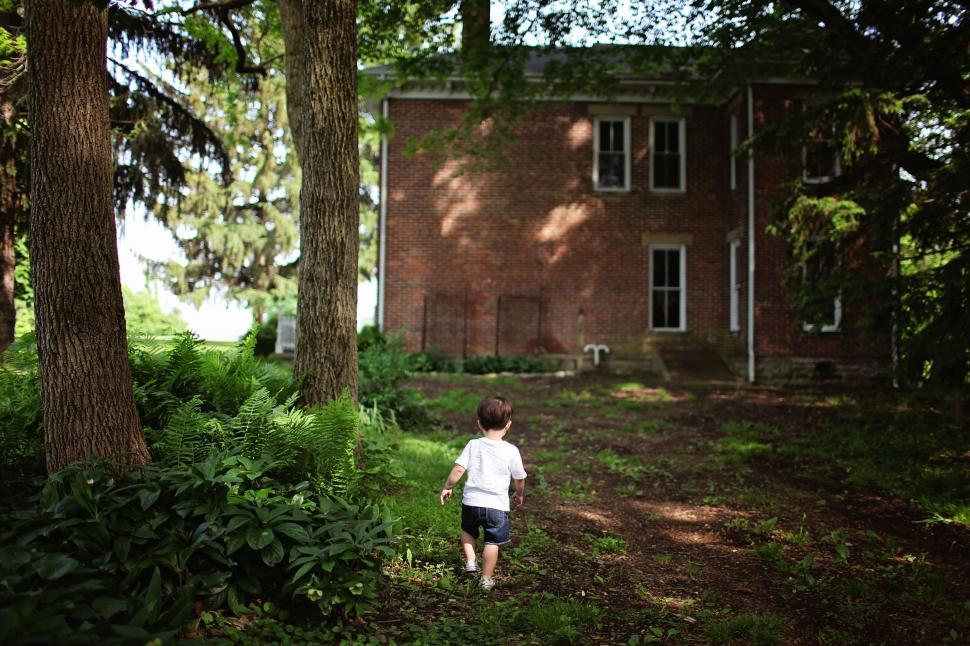 Free Image of Little Boy walking towards red brick house 