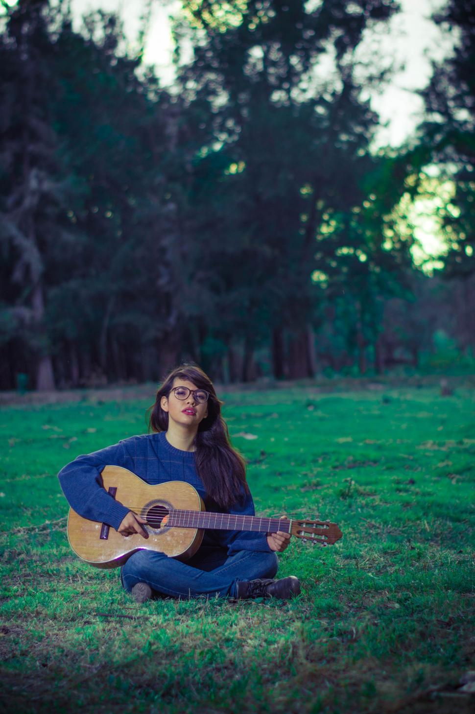 Free Image of Female Guitarist in park - looking at camera  