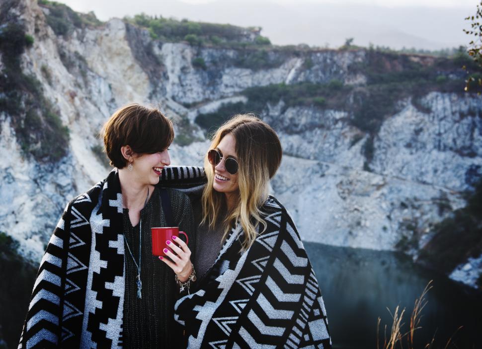 Free Image of Two young Caucasian women wrapped in a blanket outdoors 