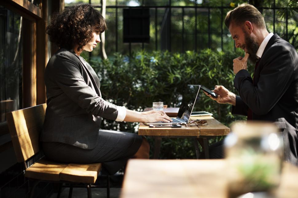 Free Image of Two business people meeting and talking at an outdoor restaurant table 