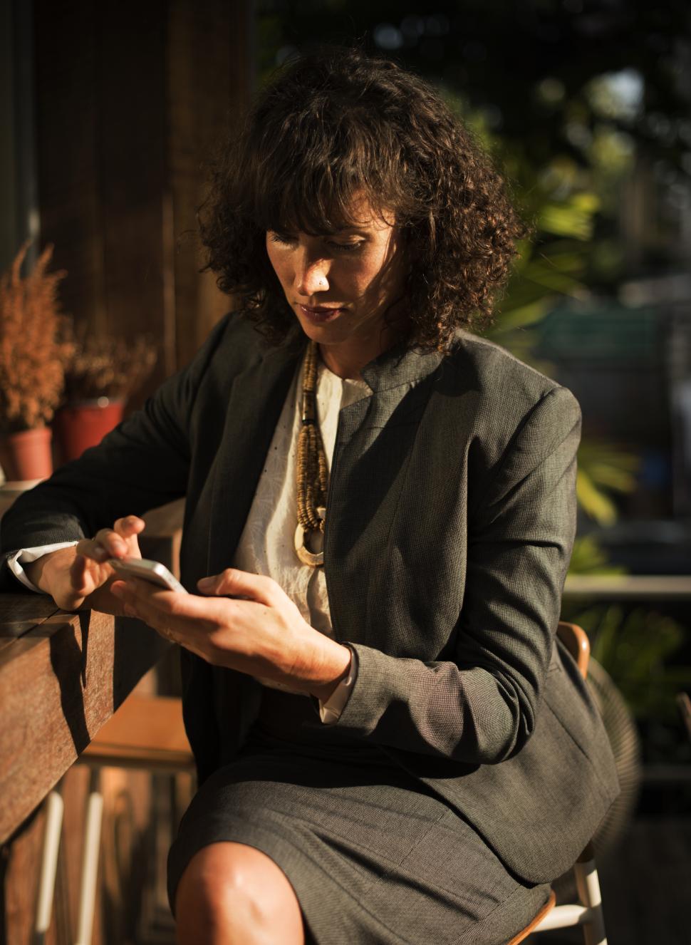Free Image of A woman looking at her mobile phone, sitting outside 
