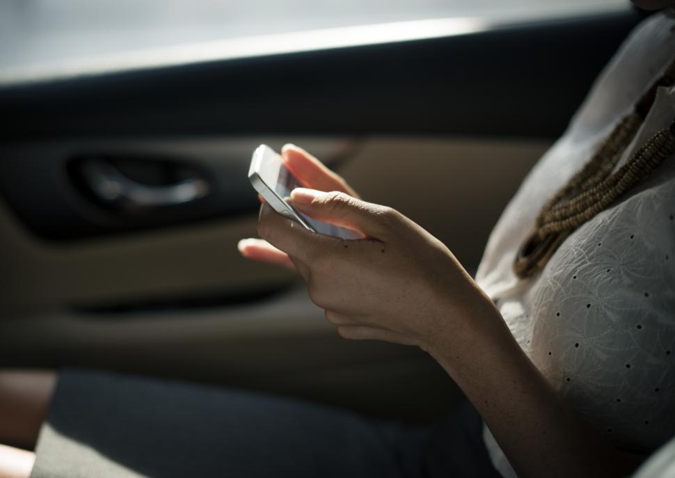 Free Image of Woman sitting in a car looking at her mobile phone 