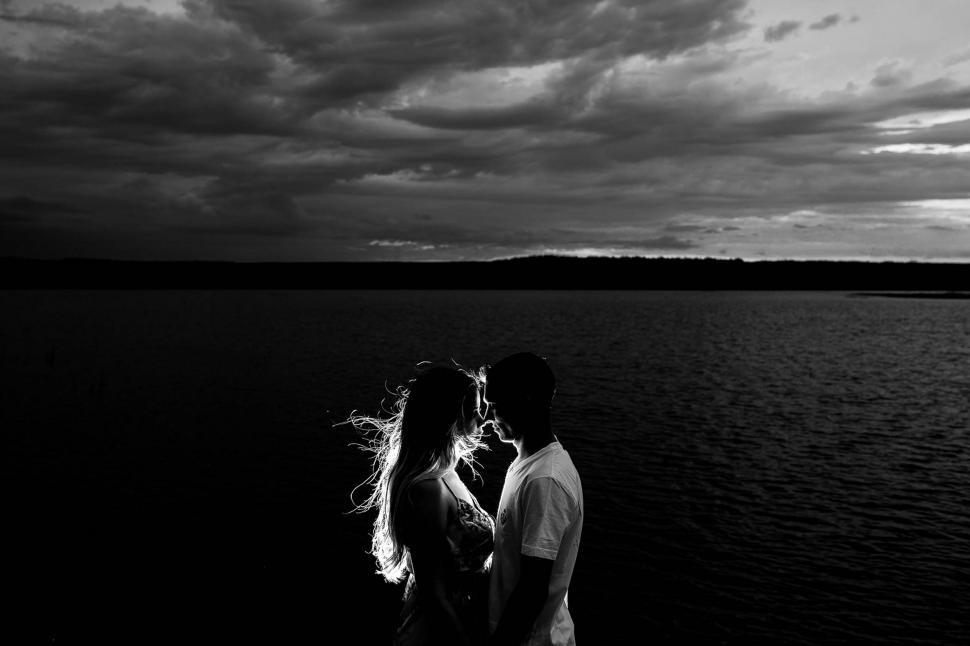 Free Image of Couple and Ocean With Black Cloudy Sky 