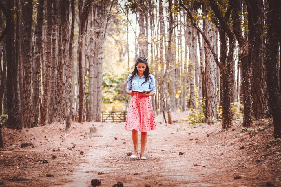 Free Image of Woman Walking and Reading in the forest 