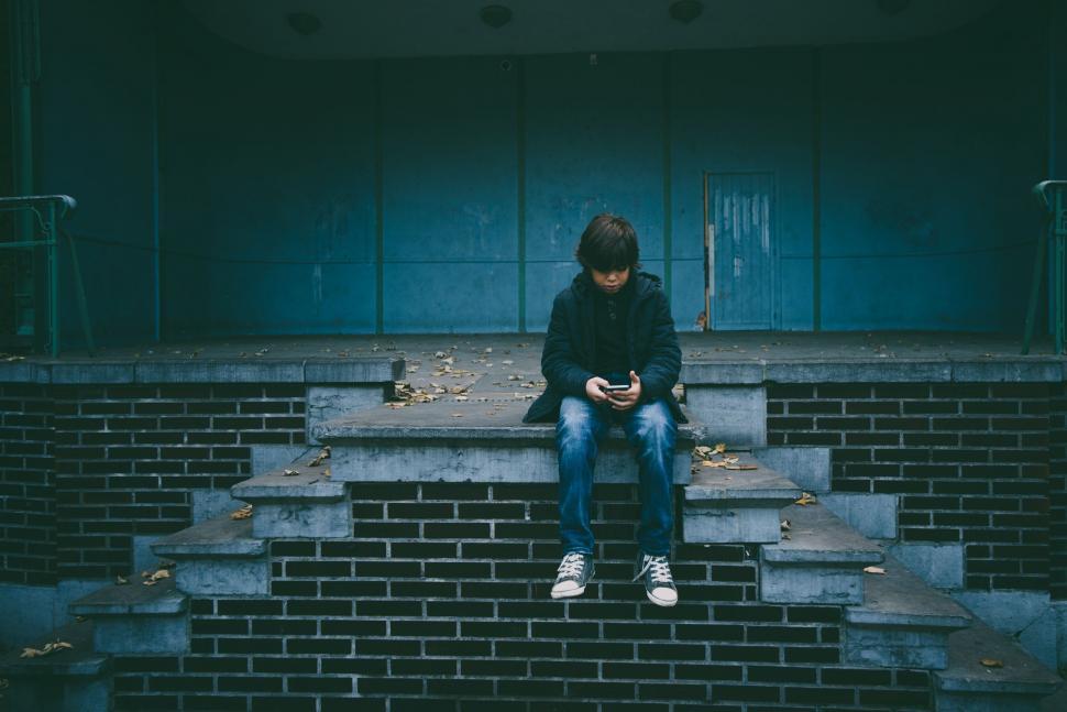 Free Image of Young Boy Using Cellphone on Stairs 