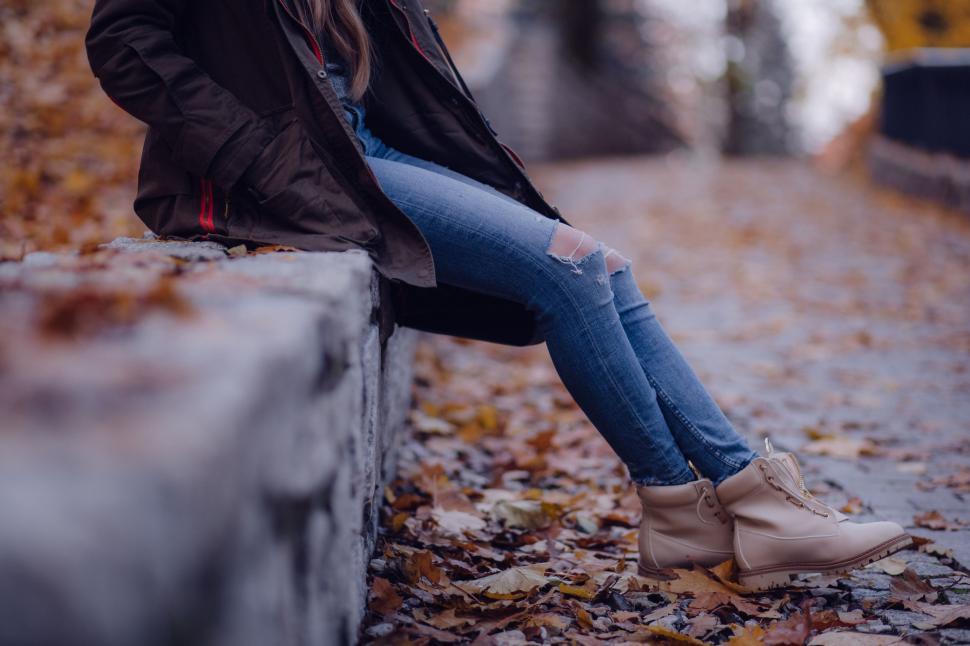 Free Image of Woman in ripped jeans with autumn leaves  