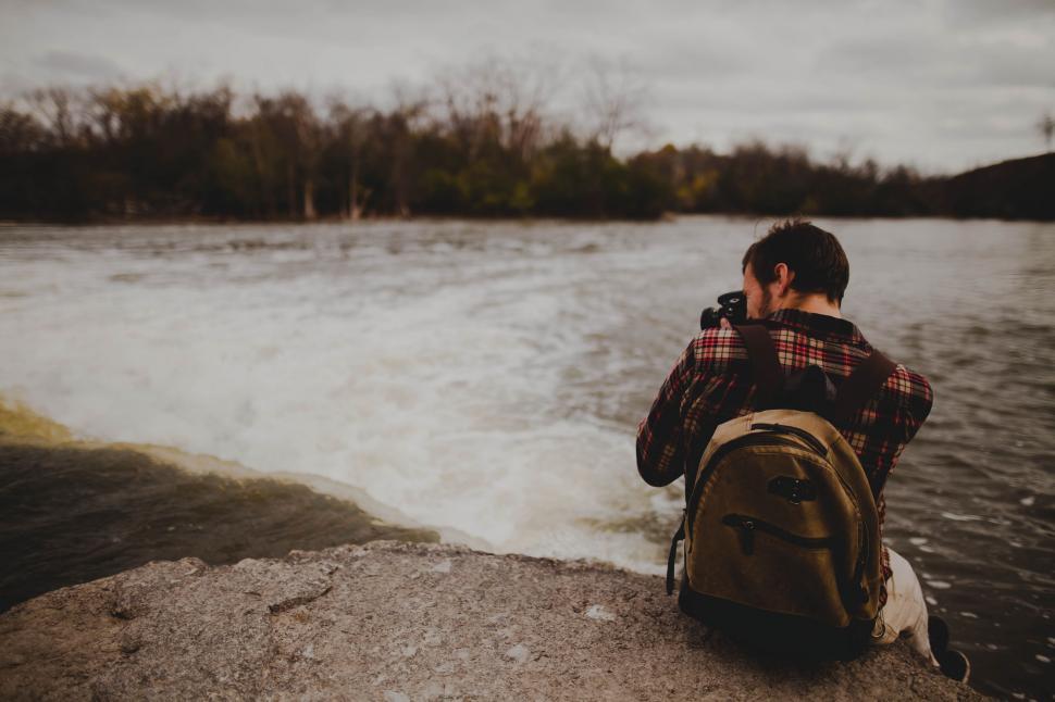Free Image of Backside view of photographer sitting at lake  