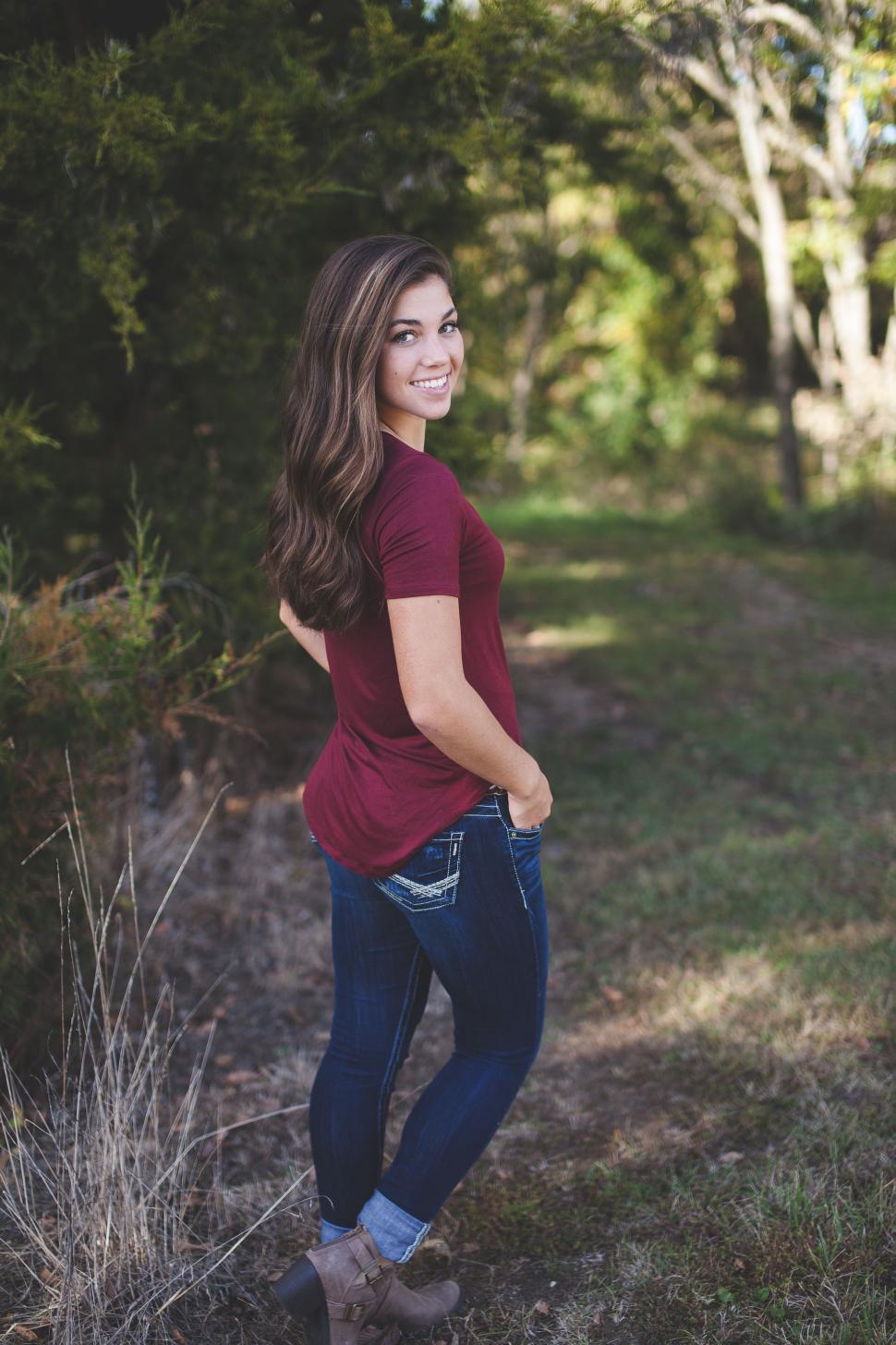 Free Image of Rear full view of smiling woman in casual clothing standing in the park  