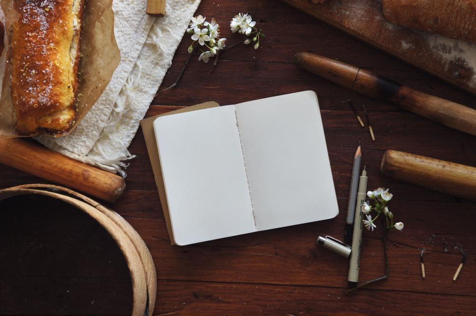 Free Image of Open Notebook and Pastry on wooden table  